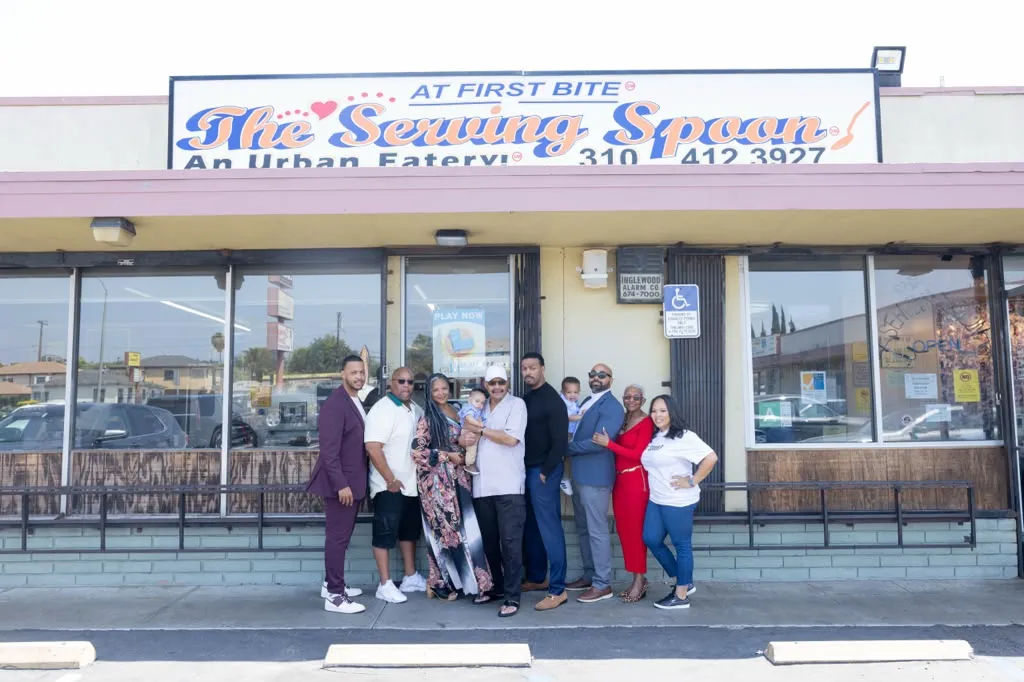 The Serving Spoon family standing together in front of the restaurant on Centinela Avenue, beneath the sign