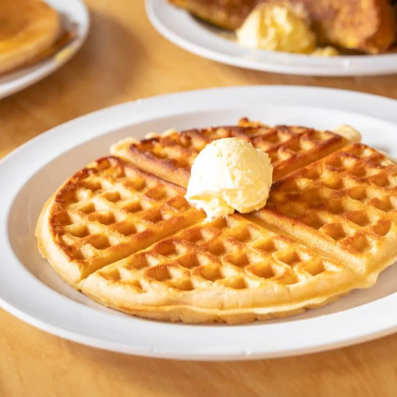 A waffle topped with a scoop of butter